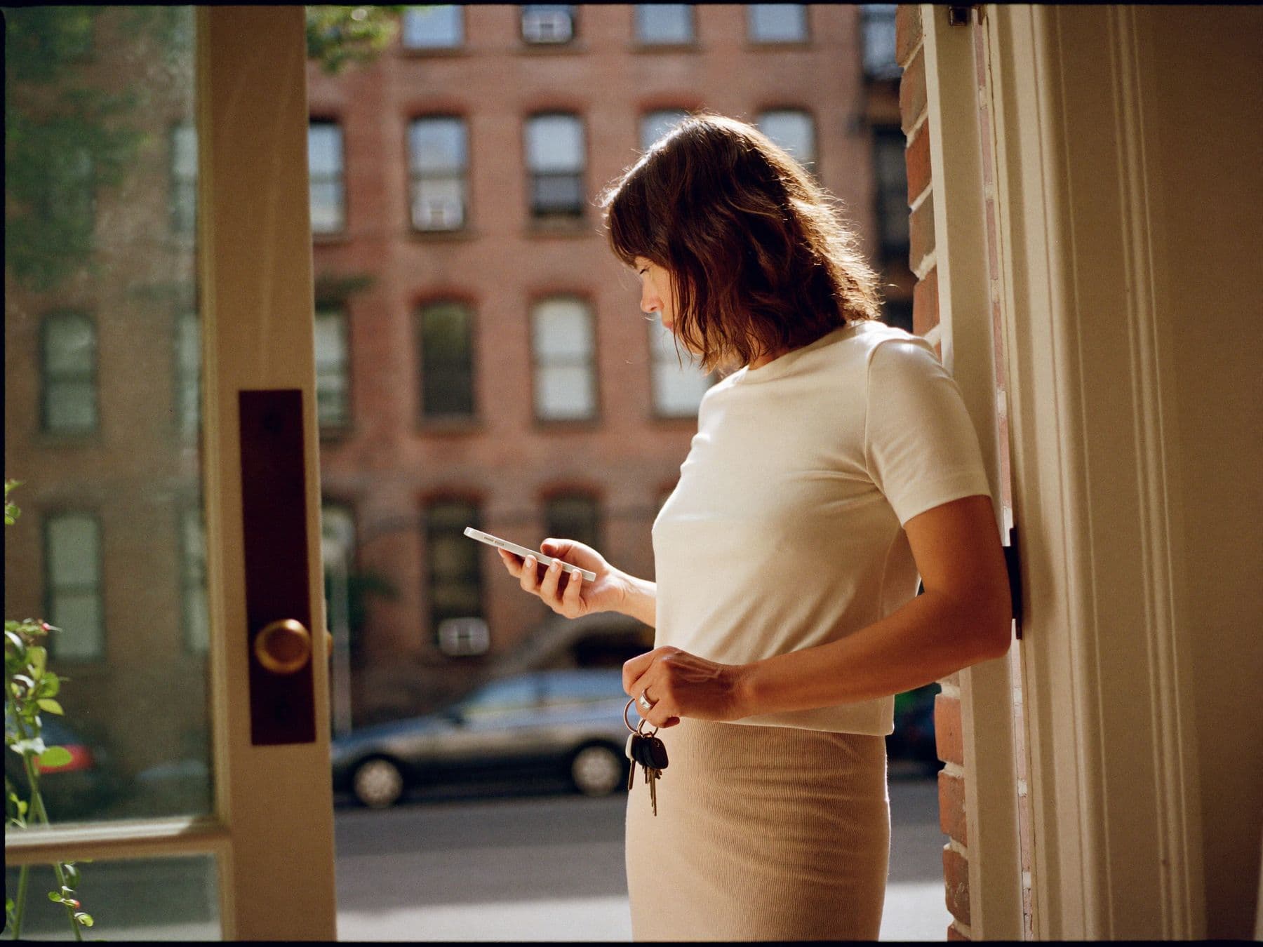 A landlord at the door of her building, reading her phone